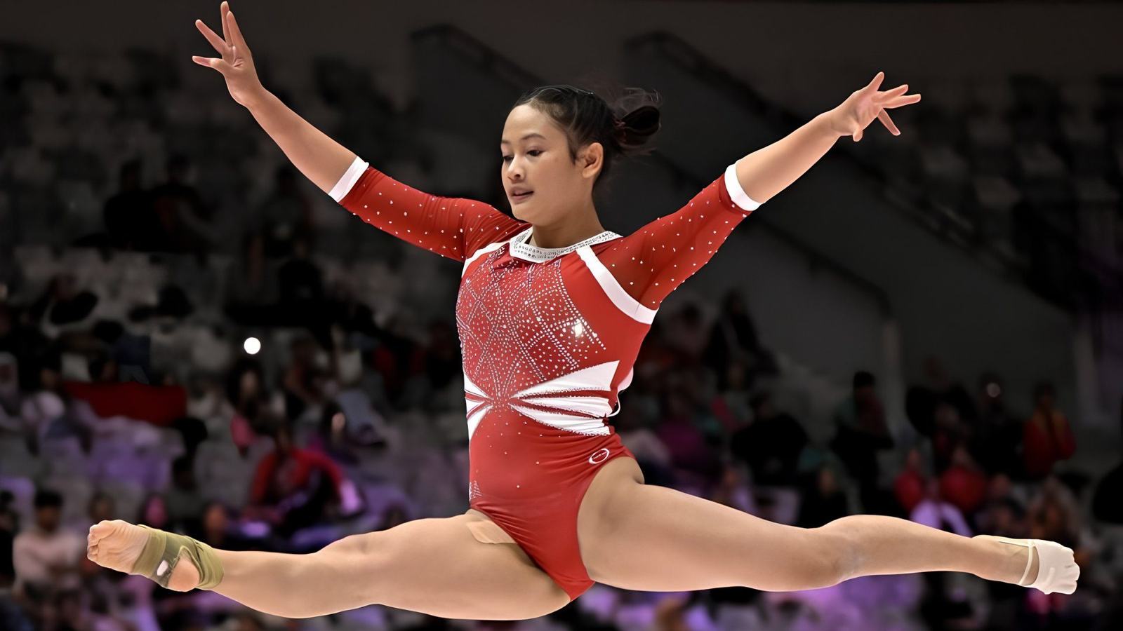 Pesenam putri melakukan lompatan split di atas balok
